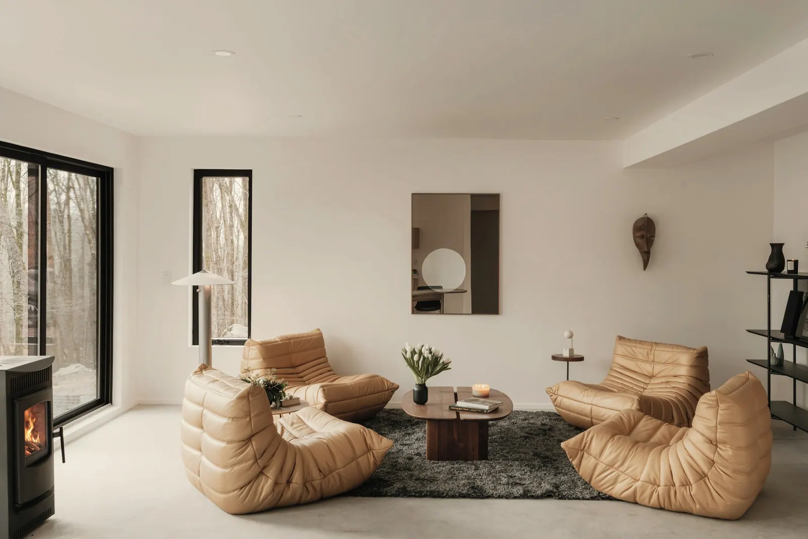 Sala de estar clara com poltronas de couro claro e lareira acesa. Imagem ilustrativa.